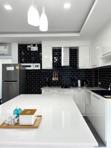 a kitchen with a white counter and black tiles at Family Cliff House - private jacuzzi with beach views in Pathiu
