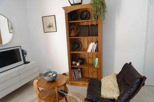 ein Wohnzimmer mit einem TV, einem Stuhl und einem Tisch in der Unterkunft Les Hauts de Saint Siffret in Saint-Siffret