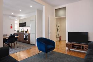 a living room with a tv and a blue chair at Invicta Premium - Downtown apartment in Porto