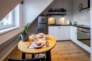 a small kitchen with a wooden table with dishes on it at Apartament Zakatek z miejscem parkingowym in Bielsko-Biała