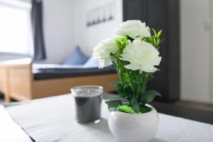 um vaso branco com flores brancas sobre uma mesa em Heide Ferienwohnung Süd em Schneverdingen