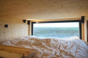 a bed in a room with a large window at Tiny House Nature 12 Innenlage - Green Tiny Village Harlesiel in Carolinensiel