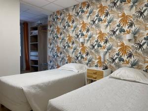 Hôtel La Vigneraie في Levens: سريرين في غرفة نوم مع ورق جدران زجاجي
