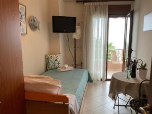 1 dormitorio con cama, TV y balcón en Maria's Apartment, en Tsoutsouros