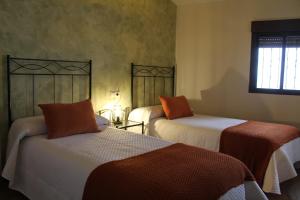 sypialnia z 2 łóżkami z pomarańczową i białą pościelą w obiekcie EL CORRAL DE LA VERA w mieście Losar de la Vera