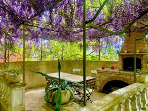 un patio con una mesa y un árbol con flores púrpuras en LA MUSCADELLE : le calme du sud de la France, en Marseillette