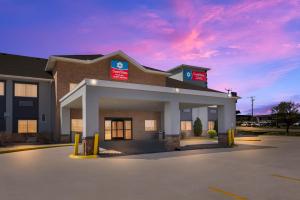 a hotel building with a sunset in the background at SureStay Plus Hotel by Best Western Topeka in Topeka