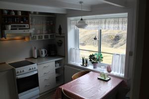 eine Küche mit einem Tisch und einem Fenster in der Unterkunft Stay in Iconic Saksun, Authentic Faroese Cottage in Saksun