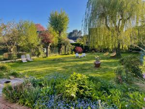 un jardín con bancos, árboles y flores en La Demeure Marcquoise, en Marcq-en-Baroeul