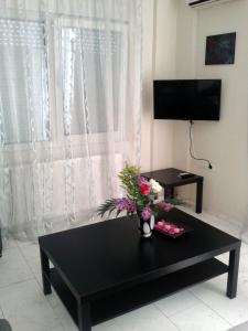 a living room with a black table with a vase of flowers at Estia in Orestiada