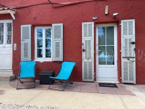 twee blauwe stoelen buiten een rood gebouw bij La Bibiane Beaulieu sur mer !!! in Beaulieu-sur-Mer