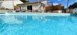a large blue swimming pool with chairs and a house at Gîte myosotis Piscine Privée 4 Chambres in Lagorce