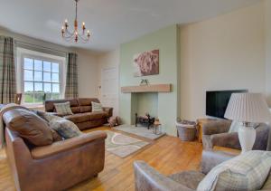 a living room with leather furniture and a flat screen tv at Trefnant Hall in Welshpool