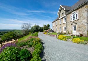 una casa de piedra con un camino de grava delante de ella en Trefnant Hall, en Welshpool