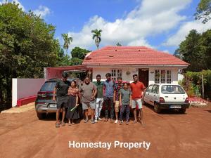 un groupe de personnes debout devant une maison dans l'établissement Homestay In Coorg Doddakallu Betta, à Somvārpet