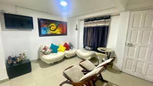 uma sala de estar com cadeiras brancas e uma televisão em Casa Family 5 em Cartagena das Índias