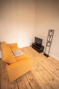 ein Wohnzimmer mit einem gelben Sofa und einem TV in der Unterkunft LE MONDRIAN - Hôtel de ville - Confort - Paisible - Wi-Fi in Saint-Étienne