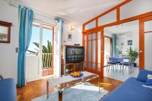 un soggiorno con un divano blu e una TV di Apartments Teo a Podgora