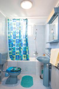 e bagno con tenda per la doccia, servizi igienici e lavandino. di Apartments Teo a Podgora