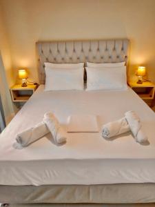 Una cama con dos pares de zapatillas. en Oliveto e mare, en Sivota