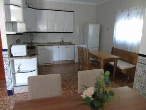 eine Küche mit weißen Schränken sowie einem Tisch und Stühlen in der Unterkunft Casa El Molino in Montecorto