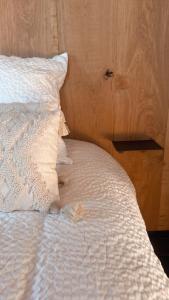 un letto bianco con cuscino e una parete in legno di Vakantie plezier Vlaanderen a Zedelgem