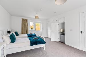 a white bedroom with a bed and a kitchen at Number 4 - Lytton Tree Lodge, Reydon, Southwold in Reydon