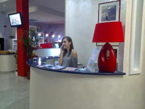 a woman sitting at a counter talking on a cell phone at Hotel Jonic in Portopalo