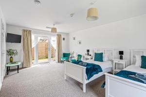 a white bedroom with two beds and a window at Number 4 - Lytton Tree Lodge, Reydon, Southwold in Reydon