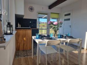 una cocina con una mesa blanca con sillas y flores en Domki na Wzgórzu Jastrzębia Góra Tupadły, en Jastrzębia Góra