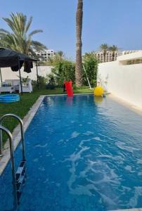a swimming pool with blue water and a palm tree at Villa ilian in Monastir