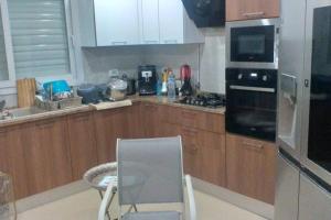a kitchen with wooden cabinets and a chair in it at Villa ilian in Monastir
