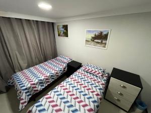 sypialnia z 2 łóżkami i komodą w obiekcie Talli Hotel w mieście Kurytyba
