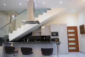 a kitchen with a counter with chairs and a staircase at AYLOL-أيلول in Qurayyah