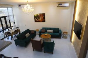 a living room with green furniture and a chandelier at AYLOL-أيلول in Qurayyah