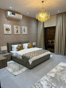 a bedroom with a large bed and a chandelier at AYLOL-أيلول in Qurayyah