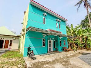 una casa azul con una motocicleta estacionada frente a ella en OYO 92521 Guest House Inayah Syariah en Yogyakarta