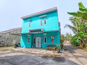 un edificio azul con un banco delante en OYO 92521 Guest House Inayah Syariah, en Yogyakarta