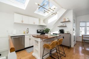 格洛斯特CbytheSea - Ocean View Penthouse的一间厨房,配有白色橱柜和一个带凳子的厨房岛 更多31张照片