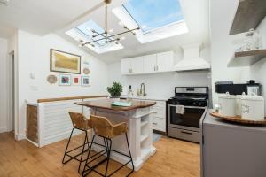 una cocina con armarios blancos y una isla con taburetes en CbytheSea - Ocean View Penthouse, en Gloucester