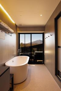 een badkamer met een bad en een groot raam bij Asama Kuzanbo in Naganohara