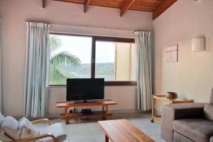 a living room with a large window and a television at San Lameer Villa 1931 by Top Destinations Rentals in Southbroom