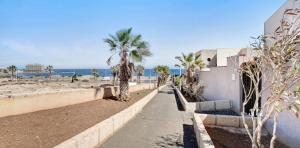 a sidewalk next to a beach with palm trees at Residencial Maresia el Medano in El Médano