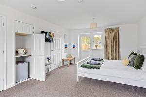 a white bedroom with a bed and a window at Number 7 - Lytton Tree Lodge, Reydon, Southwold in Reydon