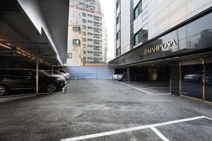a parking lot with cars parked in front of buildings at Mariposa Hotel Songtan in Pyeongtaek