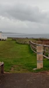 a field with a fence and the ocean in the background at Crimdon dene bay view holiday home NO SMOKING NO PETS in Durham