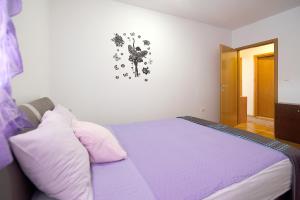 a bedroom with a bed with purple sheets and pillows at Lungo Mare Apartment with Terrace in Pula