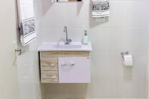 een witte badkamer met een wastafel en een raam bij Apê 2 in Sao Paulo