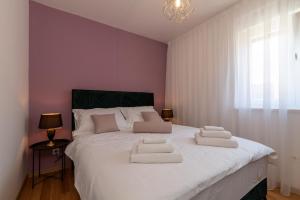 a bedroom with a large white bed with three pillows on it at Infinity Residence in Trogir