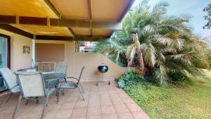 a patio with a table and chairs and a palm tree at San Lameer Villa 2502 by Top Destinations Rentals in Southbroom